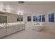 Bright main bathroom featuring a freestanding tub, vanity with dual sinks and natural lighting at 3235 S Tioga Way, Las Vegas, NV 89117