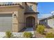 Close-up of a home entrance with a covered porch, desert landscaping, and a side-entry garage at 371 Triple Falls St, Indian Springs, NV 89018