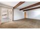 Spacious living room featuring exposed beams, sliding glass doors to patio and neutral carpet at 4690 San Benito St, Las Vegas, NV 89121