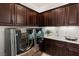 Spacious laundry room with dark wood cabinets, modern washer and dryer, and a sink at 50 Carolina Cherry Dr, Las Vegas, NV 89141