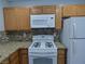 A kitchen with wood cabinets, granite counters, mosaic backsplash, and white appliances at 5044 S Rainbow Blvd # 106, Las Vegas, NV 89118