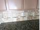 Close-up of kitchen tile backsplash with granite countertop and neutral-colored cabinets at 5115 Blossom Ave, Las Vegas, NV 89142