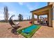 Relaxing backyard area with putting green, rock landscaping, and covered patio at 5467 Eleganza Ave, Pahrump, NV 89061