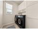 Modern laundry room featuring a washer, dryer, cabinets, and a bright window at 5467 Eleganza Ave, Pahrump, NV 89061