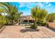 Expansive backyard featuring a lush lawn, mature trees, stone patio, and a view of the two-story home with a balcony at 5872 Revital Ct, Las Vegas, NV 89131