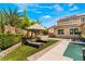 Backyard offers a relaxing outdoor space with lounge chairs, an umbrella, lush greenery, and a partially visible pool at 5872 Revital Ct, Las Vegas, NV 89131