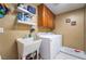 Functional laundry room with a utility sink, washer, dryer, storage cabinets, and tiled floor at 5872 Revital Ct, Las Vegas, NV 89131