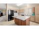 Kitchen with an island, modern appliances, tile floors, and light wood cabinets at 5934 Reflection Point Ct, Las Vegas, NV 89110