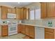 Bright kitchen featuring wood cabinets, light countertops, white appliances, and natural light at 6059 Saddle Horse Ave, Las Vegas, NV 89122