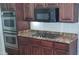 Close up of kitchen features stainless steel ovens, cooktop, granite counters and wood cabinets at 6120 Matisse Ave, Las Vegas, NV 89131