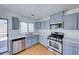 Well-lit kitchen with stainless steel appliances, light wood flooring, and light blue cabinets at 6552 Coldwater Bay Dr, Las Vegas, NV 89122