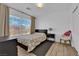 Bright bedroom with laminate wood floor, large window with blinds, bed, and a stylish accent chair at 6817 Frances Celia Ave, Las Vegas, NV 89122