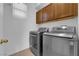 Modern laundry room featuring front loading washer and dryer set with brown cabinets above at 6817 Frances Celia Ave, Las Vegas, NV 89122