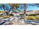 Charming single-story home with a well-maintained lawn and driveway, surrounded by mature trees and greenery at 6944 Emerald Springs Ln, Las Vegas, NV 89113