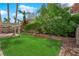 Beautiful backyard with lush landscaping, a retaining wall, and a cozy pergola seating area at 7213 Buglehorn St, Las Vegas, NV 89131