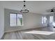 Spacious living room with wood-look floors, a large window, and modern lighting at 7437 Lattimore Dr, Las Vegas, NV 89128