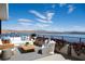 Outdoor seating area with plush seating, a wooden coffee table, and bright flowers overlooking a scenic waterfront view at 1572 Pleasant Bay Ct, Henderson, NV 89011