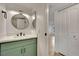 Bright bathroom featuring a modern round mirror, sleek lighting, and a green vanity with matte black hardware at 163 Spinnaker Dr, Henderson, NV 89015