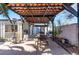 Exterior patio area with a dining table, kitchen area and decorative wood frame overhead at 1920 Parkchester Dr, Las Vegas, NV 89108