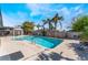 Backyard swimming pool surrounded by lush palm trees, lounge chairs, and a covered patio at 1920 Parkchester Dr, Las Vegas, NV 89108