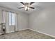 The neutral-toned bedroom features tile floors, a ceiling fan, and a large window to allow natural light in at 3047 Whispering Crest Dr, Henderson, NV 89052