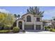 Two-story home featuring a front yard with mature landscaping, a two car garage and classic desert architecture at 3047 Whispering Crest Dr, Henderson, NV 89052