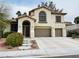 Beautiful two-story home with an arched entryway, lush landscaping, and a spacious driveway leading to a three-car garage at 3047 Whispering Crest Dr, Henderson, NV 89052