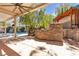 Inviting covered outdoor kitchen space featuring stone surround, verdant landscaping, and sparkling swimming pool at 3047 Whispering Crest Dr, Henderson, NV 89052