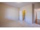 A carpeted bedroom with an open closet space and hallway access at 324 S Lisbon St, Henderson, NV 89015