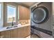 Contemporary laundry room featuring sleek cabinets, modern appliances, and stylish sink with window at 4077 Heron Fairway Dr, Las Vegas, NV 89141