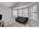 Bright sitting room featuring white shutters, wood-look floors and a comfortable black futon couch at 5429 Painted Sunrise Dr, Las Vegas, NV 89149