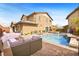 A spacious backyard featuring a swimming pool with a spa, an outdoor kitchen, and comfortable seating at 5523 Kyle Peak Ct, Las Vegas, NV 89135