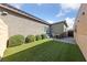 Landscaped backyard featuring artificial turf, a small table and chairs, and manicured shrubbery, creating a charming outdoor space at 6192 Lautman Ridge Ct, Las Vegas, NV 89141