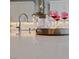 A closeup of beautiful quartz countertops, a sleek faucet, and elegant pink glassware in a modern kitchen at 6192 Lautman Ridge Ct, Las Vegas, NV 89141