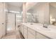 Bright bathroom with double sinks, white cabinetry, large mirror, and a glass-enclosed shower with a bench at 758 Marigold Sunrise St, Henderson, NV 89011