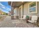 Charming front porch with seating and decorative plants, featuring a brick pathway, gravel landscaping, and neutral colored walls at 758 Marigold Sunrise St, Henderson, NV 89011