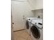 Bright laundry room featuring a modern washer and dryer set next to a door and complimented by shelving at 8212 Calico Wind St, Las Vegas, NV 89131