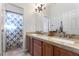 Bathroom with double sinks, wooden cabinetry, granite countertops, and shower with blue starfish curtain at 10129 Elk Valley St, Las Vegas, NV 89178