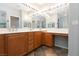 Bright bathroom featuring double sinks, wood cabinets, large mirrors, and tiled floors at 10288 Grizzly Forest Dr, Las Vegas, NV 89178