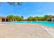 Expansive community pool with ample deck space surrounded by lush landscaping, and neighborhood buildings at 10288 Grizzly Forest Dr, Las Vegas, NV 89178