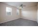 This bedroom features neutral walls, carpet, two windows, and a ceiling fan at 10956 Hunting Hawk Rd, Las Vegas, NV 89179