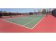 A wide view of a neighborhood tennis court surrounded by dark fencing and green and red surface at 1401 Via Savona Dr, Henderson, NV 89052