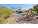 Lush backyard retreat featuring a sparkling pool, patio, mature trees, and rock landscaping for outdoor enjoyment at 1634 Georgia Ave, Boulder City, NV 89005