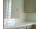 The kitchen has tiled floors, wooden cabinets and white tile countertops with a window at 1851 Hillpointe Rd # 2112, Henderson, NV 89074