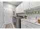 Well-lit laundry room with gray washer/dryer, white cabinetry and a sink at 2140 Idaho Falls Dr, Henderson, NV 89044
