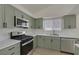 Updated kitchen features stainless steel appliances, sage cabinets, and light countertops at 239 Highgate St, Henderson, NV 89074