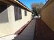 A concrete pathway alongside a home with stucco walls, red rock landscaping, and desert-style architecture at 3507 Pointe Vedra Ct, Las Vegas, NV 89122