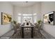 Modern dining room with a long table, seating for six, and framed pictures hanging on the white walls at 3710 E Oquendo Rd, Las Vegas, NV 89120