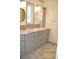 Well-lit bathroom with dual sinks, marble countertops, and sleek gray cabinetry for a modern aesthetic at 4417 Rita Dr, Las Vegas, NV 89121