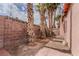 Backyard featuring a brick wall, palm trees, loose dirt and a pink home exterior at 5016 Roswell St, Las Vegas, NV 89120